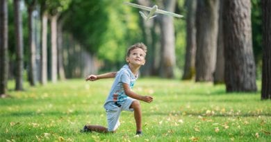 boy-playing-with-toy-glider-in-park-on-summer-day-PTXPHJC