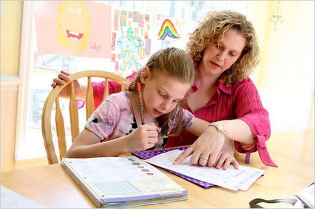 A nursery school teacher stands by the child